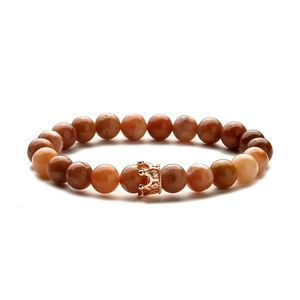 Detail von Roségold-Kronenanhänger an braunem Achat-Perlenarmband