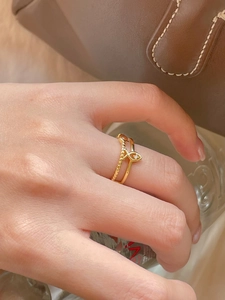 Macro shot of minimalist gold double-layered fish ring with a sparkling zircon inlay