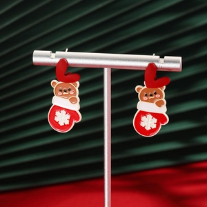 Close-up of festive Christmas earrings featuring red gloves and brown bear designs