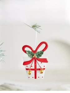 Detail of white polka dot gift box ornament with red bow and gold bells on tree