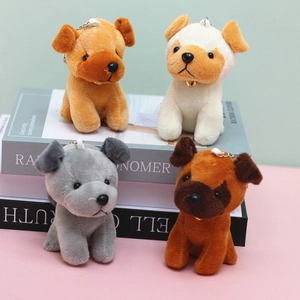 Close-up of four plush puppy keychains in brown and white on a book background