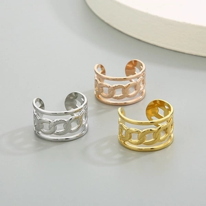 Gros plan de trois ear cuffs style chaîne en argent, or et or rose sur fond mat uni