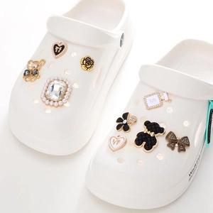Detail shot of golden metal charms with pearls, camellias, and bears for clogs decoration