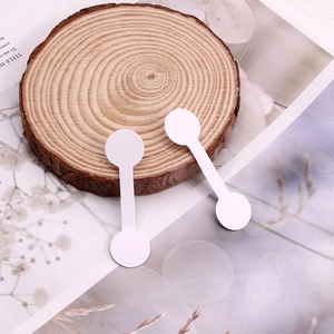 Close-up of white dumbbell jewelry tags on a rustic wooden slice for price labeling