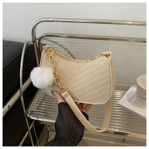 Détail du sac sous le bras en feutre beige avec matelassage en V et pompon doux