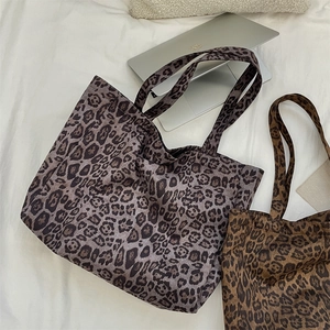Top view of large leopard print tote bags in grey and brown next to a laptop