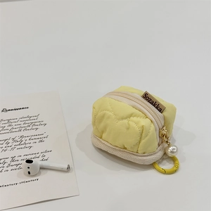 Detail of yellow quilted heart-stitched pouch for AirPods with pearl charm and hook