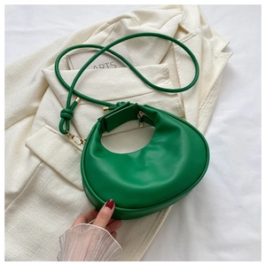 Detail of a bright green half-moon PU leather handbag with gold zipper and knotted strap
