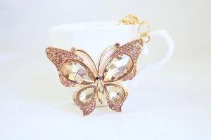 Detail of a champagne crystal butterfly keychain with gold lobster clasp and rhinestones