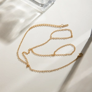 Detailed close-up of a minimalist gold finger chain bracelet with elegant light reflections