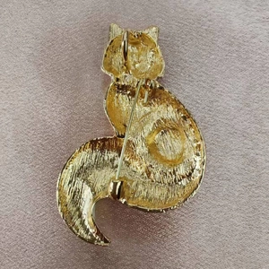 Détail de l'arrière d'une broche renard dorée montrant l'épingle et la texture