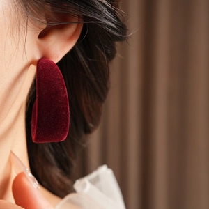 Close-up of deep red velvet C-shaped hoop earring showing soft flocking texture and detail