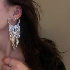 Close-up of heart-shaped zircon tassel earrings in gold finish on a model