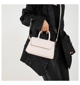 Close-up of stylish cream white PU leather square handbag with top handle and strap