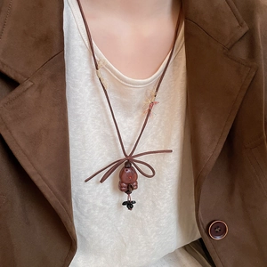 Detail of a vintage brown leather cord necklace with a bear pendant and bow tie element