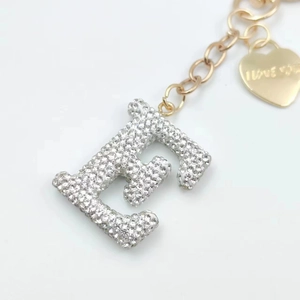 Detail of golden letter E keychain with pavé crystals and heart I Love You tag