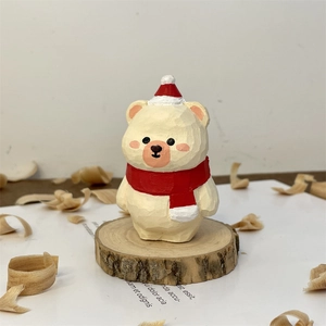 Close-up of hand-carved wooden Christmas bear with red hat and scarf on wood base