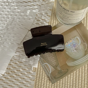 Detail of elegant dark brown acetate hair claw clip with golden Borrèlic La France text