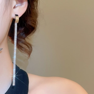 Close-up of golden tassel earrings with sparkling zircon crystals worn by a model