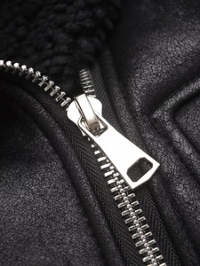 Détail d'une fermeture éclair en métal argenté sur un gilet noir en cuir avec peluche