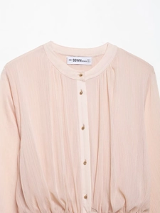 Close-up of pink pleated dress fabric with elegant gold semi-round buttons and collar detail
