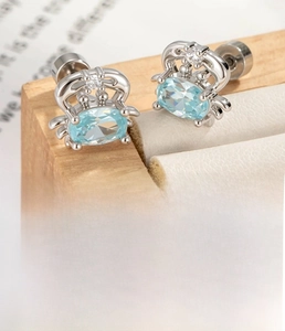 Macro shot of silver crab stud earring with light blue zircon and steel screw back