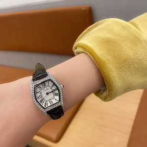 Detail of silver tonneau watch with rhinestones and black leather strap on wrist