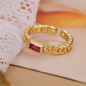 Detail of adjustable gold chain ring with emerald-cut red zircon on textured fabric