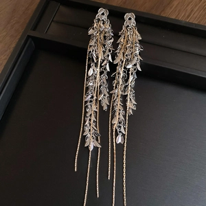Détail de boucles d'oreilles élégantes à pampilles blé or et argent sur plateau noir