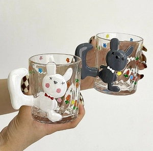 Close-up of glass cups with 3D rabbit-shaped handles and floral carrot patterns