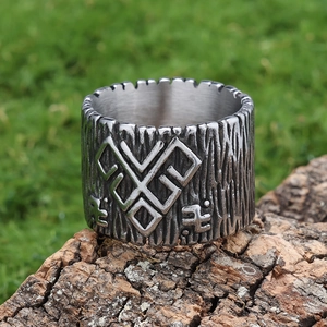 Macro shot of silver textured viking ring with bark patterns on a rustic wooden base
