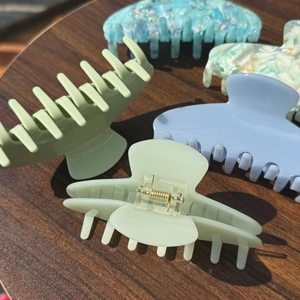 Detail of teal and mint acetate claw clips showing marble texture on a wooden desk