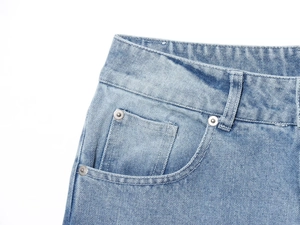 Detailed close-up of light blue denim waistband featuring metallic studs and precision stitching