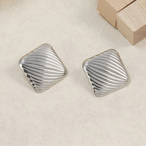 Minimalist square silver earrings with wave texture on a modern off-white display surface