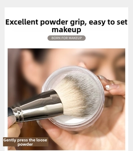 Macro shot of fluffy powder brush picking up loose powder for a flawless makeup finish