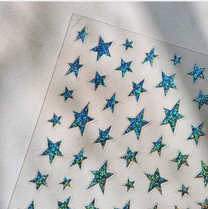 Macro shot of 3D silver holographic star nail stickers with blue-green glitter texture