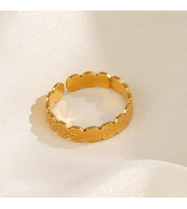 Detail of gold hammer textured ring surface on white silk fabric background