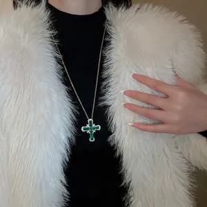 Collier croix doré élégant avec zircon vert émeraude et gemmes blanches sur un mannequin