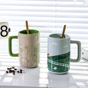 Detailed view of two ceramic mugs with floral and pastoral patterns and wooden spoons