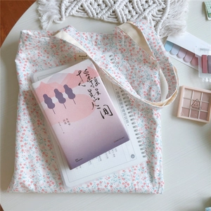 Flachbild einer geblümten Canvas-Tasche mit kleinen Blumen und Alltagsgegenständen