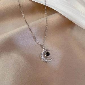 Detail of silver moon pendant with black projection stone and crystal inlays