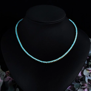 Close-up of a 3mm turquoise tennis necklace in gold-plated brass on a black neck bust