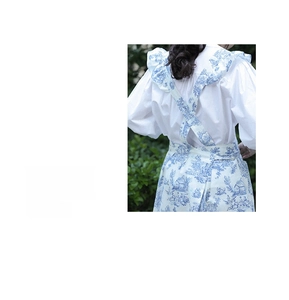 Detail of cross-back floral apron with ruffled edges and blue French pattern