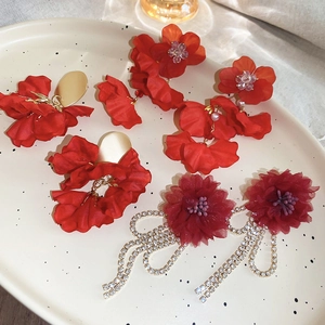 Macro shot of red floral earrings with silk fabric petals and luxury rhinestone tassels