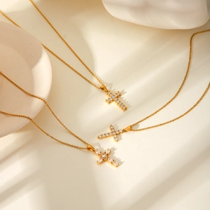 Detailed view of three gold-plated cross necklaces with zircon inlays on display