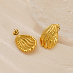 Détail de boucles d'oreilles dorées 18K avec texture coquillage sur soie champagne