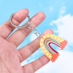 Macro detail of acrylic rainbow keychain with heart pattern against a blue sky background