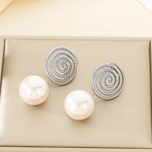 Detail of silver spiral textured metal earrings featuring a large iridescent pearl drop