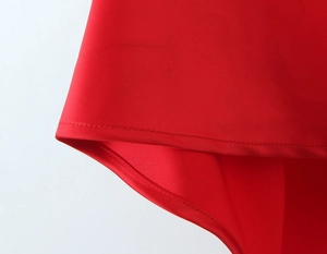 Macro view of high-quality double stitching on glossy red satin fishtail dress hem