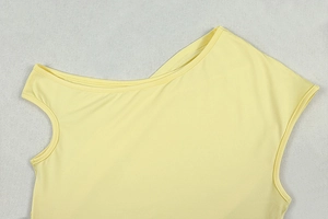 Detail of the yellow knitted dress showing asymmetrical neckline and precise stitching